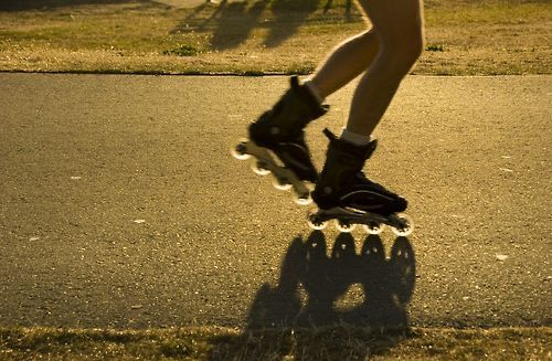 Roller skates moving across sunlit pavement